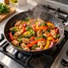Salteado de pollo con brócoli, pimentón y cebolla en un sartén sobre una estufa a gas, receta fácil para hacer en casa en menos de 30 minutos
